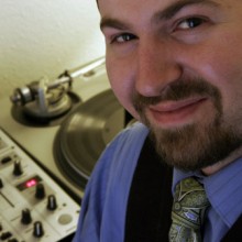 John Murray, a man wearing a tie, stands in front of a turntable.