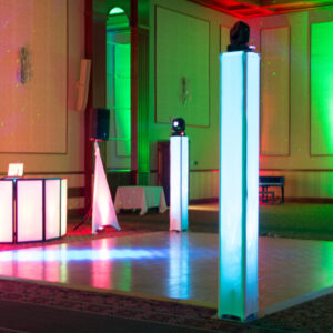 A dance floor set up with vibrant green and red lights, accompanied by professional lighting equipment.