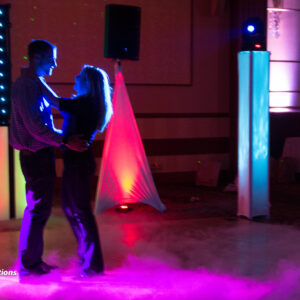 A couple dancing on a stage with colorful lights.