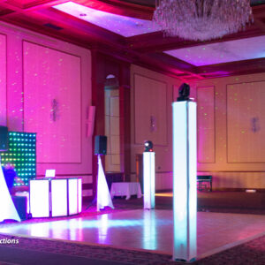 Dj set up in a ballroom with colorful lights.