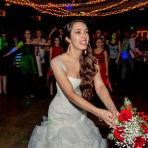 A bride dancing with her bouquet at a wedding reception.