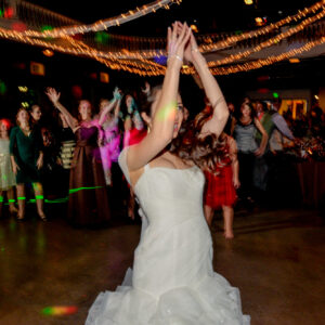 A woman in a wedding dress is dancing with her hands in the air.
