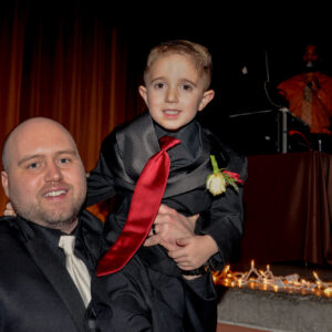 A man in a black suit holding a young boy.