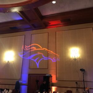 The Denver Broncos logo is projected on the ceiling at corporate parties.