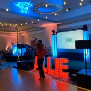 A person standing on a stage with a sign that says "allie" at a georgia corporate event.