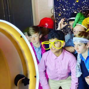A group of boys are posing for Bat/Bar Mitzvah pictures in front of a mirror.