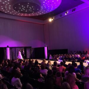 A group of people watching a fashion show on a stage.