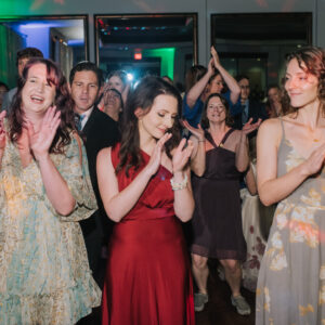 A group of people clapping on the dance floor at a wedding.
