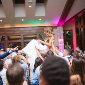 A bride being carried on the dance floor at a wedding reception.