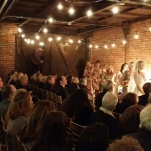 A wedding ceremony in a brick building with string lights.