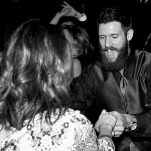 A man with a beard and a woman dancing at a party.