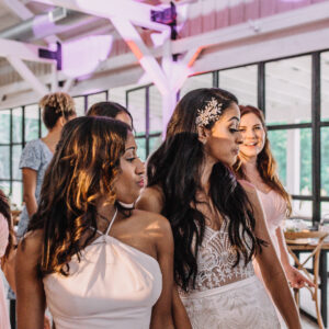 A bride and her bridesmaids are dancing in a barn.