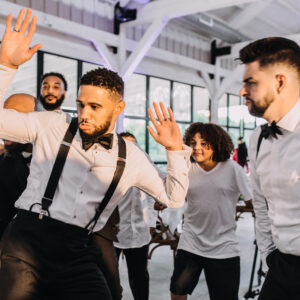 A group of men dancing at a wedding reception.