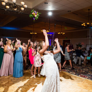 A bride throws a bouquet into the air at a wedding reception.