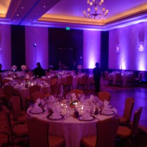 A banquet room with purple lighting and tables, perfect for a wedding reception.