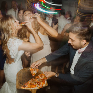 A bride and groom eating pizza at a wedding reception.