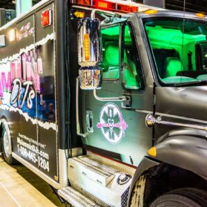 A black ambulance truck is on display at a convention.