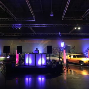 A dj set up in a museum with cars in the background.