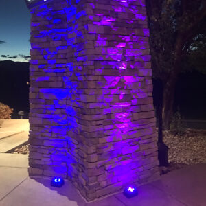 A stone pillar is lit up with purple lights.