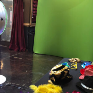 A photo booth with a green screen and hats, perfect for capturing fun and memorable moments at your school dance.