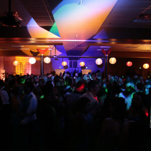 An overview of a school dance, with a crowd of people enjoying themselves.