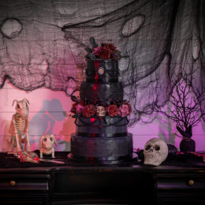 A black cake on a table with skeletons on it, masterfully crafted by a Georgia wedding DJ service.