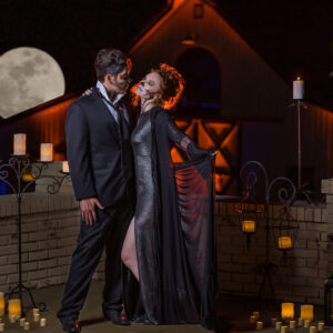 A couple in a Halloween costume standing in front of a brick wall with candles at their Georgia corporate DJ event.