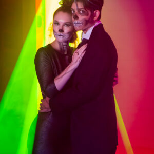 A man and woman dressed up as skeletons in front of a colorful light show at a Georgia wedding DJ event.