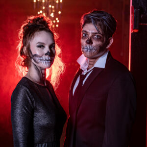 A man and woman dressed as skeletons pose for a photo in front of a photo booth rental Georgia.