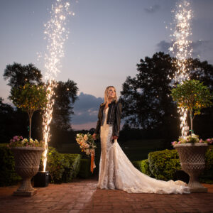 A bride with sparklers posing in front of a brick walkway, captivated by the ambiance set by a Georgia wedding DJ.