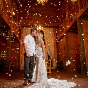 A bride and groom standing under confetti in a barn with a photo booth rental from Georgia.