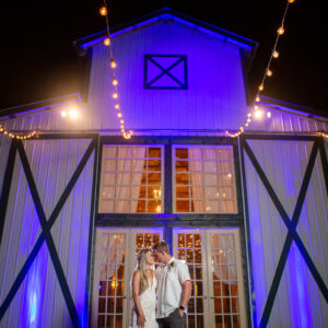 A bride and groom standing in front of a barn at night, celebrating with a Georgia wedding DJ.