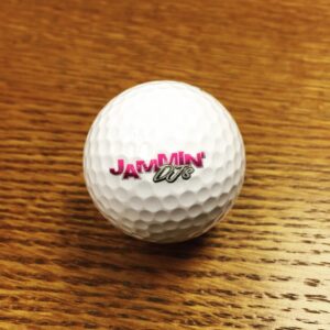 A white golf ball with a pink Georgia corporate DJ logo on it.