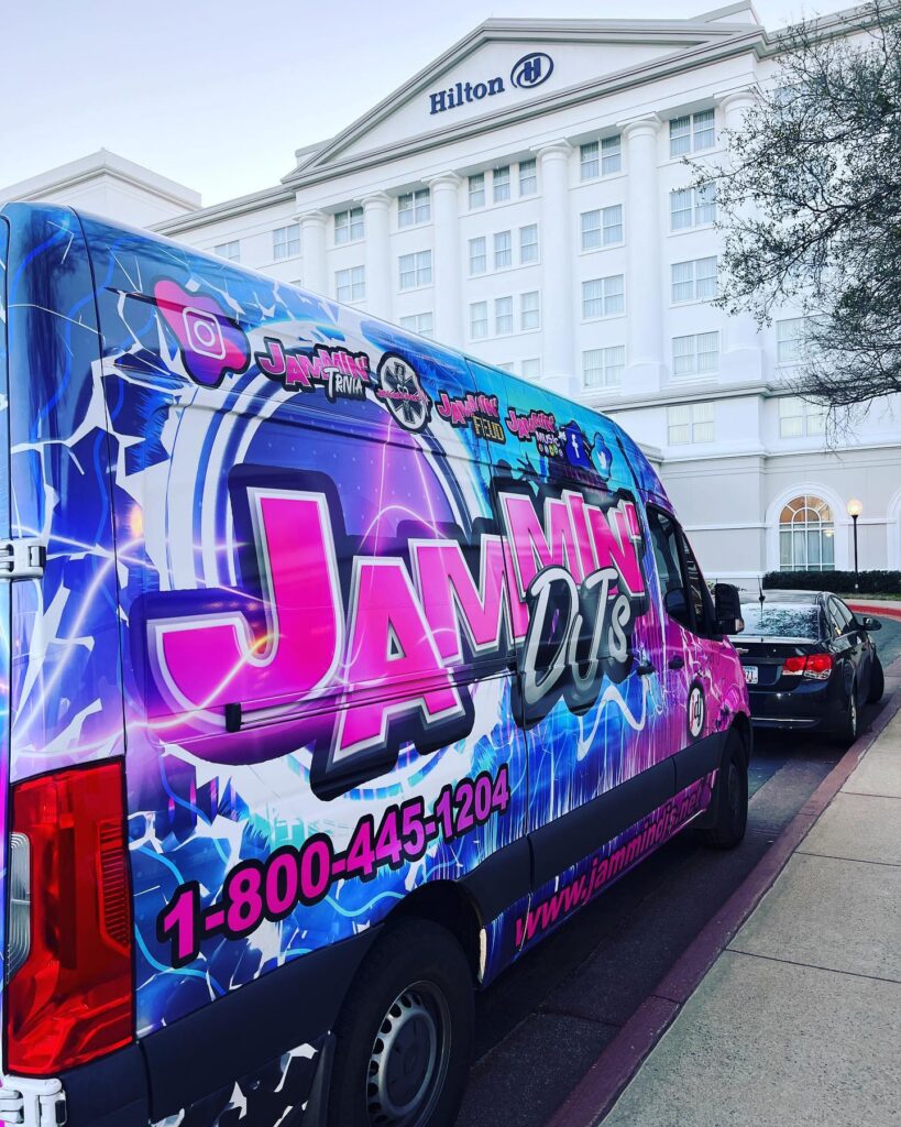 A blue and purple van parked in front of a hotel, ready for the Georgia wedding DJ's setup.