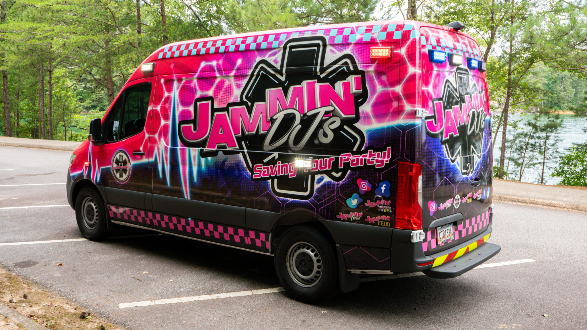 A pink and black van, offering photo booth rental services in Georgia, parked in a parking lot.