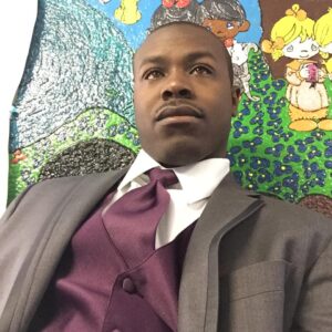 A man in a suit and purple tie sits in front of a colorful mural featuring cartoon characters, showcasing the unique artistic flair of Dericole C.