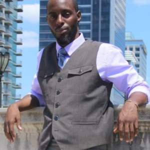 A man in a vest and tie stands by a railing, tall buildings soaring in the background, embodying the polished essence of professional DJs who bring music entertainment to life.