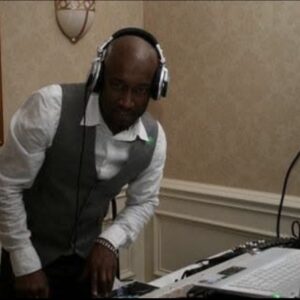 A man wearing headphones and standing in front of a laptop.