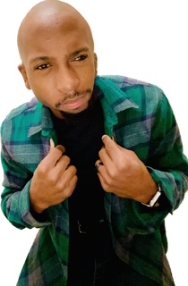 A person wearing a green plaid jacket over a black shirt, looking slightly upward while holding the jacket lapels with both hands.
